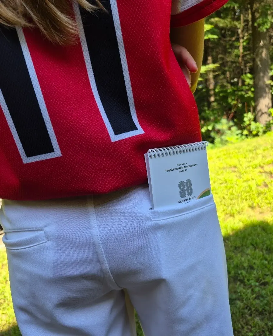 Le carnet glissé dans la poche arrière d'un pantalon de baseball blanc.